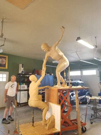 Columbine Gallery and the National Sculptors' Guild are pleased to team up with the Rotary Club of Thompson Valley on "The Legacy Project" in Loveland, Colorado. 

The Legacy Project celebrates the 30th anniversary (2019) of the Rotary Club of Thompson Valley. The bronze sculpture depicts a woman helping a teenage boy surmount a stone precipice tying into the Rotary motto, "Service Above Self". Part of this service has been the club's support of Polio Plus, a major contributor to the eradication of Polio world-wide.

"Reaching our Goal" by NSG Fellow Denny Haskew will be placed in the plaza of The Foundry, a new development that is transforming Loveland's historic downtown, set to open Fall 2018. The art placement will coincide with the opening.

The National Sculptors' Guild designed additional stone elements to activate the plaza and provide area's of recognition to the club's efforts. 

We have contributed $50,000 to the project, our way of giving back to the support we've received from this community over the past 26 years. 

Haskew is a renowned figurative artist and a Charter Member of the National Sculptors' Guild. His work is in the numerous prestigious collections including the Smithsonian Institution, the Gilcrease Museum, OK and the Boulder and Colorado Springs campuses of the University of Colorado.

​Denny Haskew currently resides in Loveland, Colorado where he is actively engaged in the art industry as a sculptor. He received his degree from the University of Utah, then served two years in the United States Army during the Vietnam War. 

Having spent numerous years as a guide and ski instructor, Denny has learned to love the rivers and mountains of the western states of Arizona, Colorado, Idaho, Oregon, and Utah.  After moving to Loveland, a hub of successful working sculptors, he wasted no time in getting monumental sculpture experience through working with renowned sculptors including Fritz White and Kent Ullberg.  Since 1987, Denny has created and placed dozens of monumental compositions; spanning the spectrum of the figurative genre.