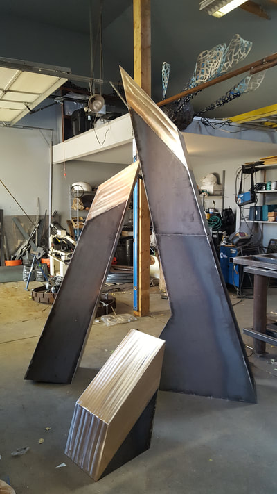 10/25/17 Update: Fabrication is nearing completion. We will be heading to Little Rock for installation soon. 4/23/17: We're pleased to announce that NSG's Stephen Shachtman won this year's Sculpture at the River Market public art competition. Stay tuned to see it actualized and installed at the Southwest Community Center. This sculpture represents a culmination of parts forming a stronger, more impactful unit as a result. The graphic nature of the sculpture is ideal for both ease of viewing while in motion and creating an iconic sculpture for the Community Center campus. Because this site incorporates so many activities and houses several public buildings, the convergence of this is represented in this form - a central piece acts as the hub of all the opportunities the campus offers. At the heart of the three steel forms is a sphere representing the community. The Steel/Bronze portion of the “A” represents Arkansas. While the individual pieces of the flagstone sphere make up my notion its people. Fabricated in CorTen steel, with a Bronze cap at the point of each pillar. The tallest form measures approximately 16-feet high. The overall footprint will span approximately 10ft wide. The center sphere is composed of stacked flagstone pieces which create the stepped sphere form. (Not a perfect smooth sphere, but stepped to create sphere appearance.) The sphere structurally helps connect the three legs, which are then bolted into cement piers. I recommend contextualizing the artwork within the broader site by placing it in a large gravel circle of grey breeze, and planting karl foerster grasses within.