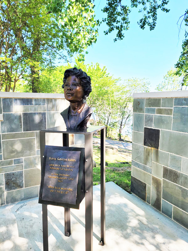 In November, the city of Little Rock installed National Sculptors' Guild Fellow Jane DeDecker's Bust of Daisy Lee Gatson Bates in Little Rock, AR.  The bronze of the civil rights activist, Arkansas NAACP president, and pioneering black journalist (1914-1999), is situated in Vogel Schwartz Sculpture Park in her former hometown. The portrait is just one acknowledgment of Bates’ legacy in the river town which also boasts a Daisy Bates Museum, several named streets, and a “Daisy Bates Day” celebrated the third Monday of February every year.  The bust also includes a plaque with a quote by the human rights advocate:   “When hate won’t die, use it for good.”  The outdoor sculpture walk winds along the Arkansas River and includes 90 works of art in its collection.   Daisy Gatson Bates, who was a mentor to the Little Rock Nine, a civil rights activist, a former Arkansas NAACP president and a pioneering Black journalist, is now commemorated with a bronze bust sculpted by Jane DeDecker and the National Sculptors' Guild, along the banks of the Arkansas River.   At-large Director Dean Kumpuris, a longtime advocate for the development of Little Rock’s riverfront, has worked to add yet another art piece to the River Market Sculpture Garden. Joining 90 other artworks, the Bates sculpture also includes a backing wall made of natural blue stones that represent the river.   Along with the new sculpture, Bates’ legacy is also celebrated at the Daisy Bates Museum, her former home and now National Historic Landmark -- also in Little Rock. The third Monday in February is recognized as “Daisy Gatson Bates Day” in Arkansas, and various streets in the state are named after her.  The city of Little Rock announced the sculpture Tuesday, and Kumpuris said, “I can think of no more fitting addition to the more than 90 artworks in the Vogel Schwartz Sculpture Garden than one honoring Daisy Bates, whose contributions to Little Rock through activism and journalism are still with us today.”  Below the bust, a plaque reads “When hate won’t die, use it for good.”   The work was donated by the nonprofit group Sculpture at the River Market, and the Little Rock Parks and Recreation Department installed it.  Leland Couch, the director of the parks department, echoed compliments of Bates. He said that it is a “distinct privilege” to honor someone who “fought so hard to make Little Rock a city for everyone.”  The Bates sculpture is near the Main Street overpass on the Eastern side of the art garden.