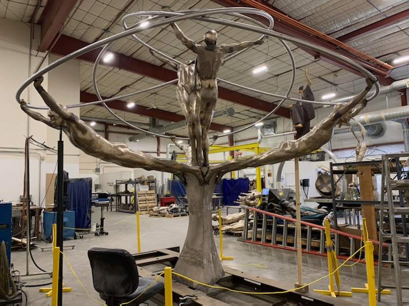 Coming soon to Downey, California...
​"Tree of Life" by Clay Enoch and the National Sculptors' Guild is in the finishing steps of bronze casting at Art Castings of Colorado.

This installation is part of a series of Public Art placements that the City has commissioned from the National Sculptors' Guild for installations in 2020. The bronze and stainless steel sculpture will be placed in a 18-foot diameter fountain at the Theater Plaza.

Our design team began working on this project in March of 2019.

Measuring 12-feet tall and 14-feet in diameter, the tree composed of eight life-size bronze figures out stretched from a single column are united by the stainless steel rings they hold; this sculpture is among our most complex figurative monuments to date. We are so excited to see this significant art statement in place. We will update this post as soon as installation is set.

Progression of the project is shown below...