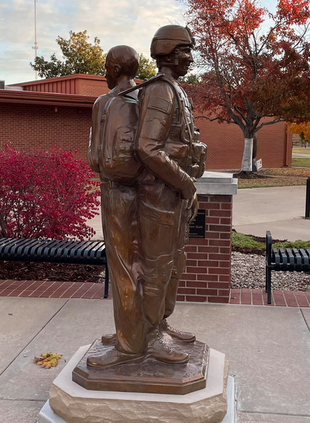 Gary Alsum’s “Tried and True” was dedicated November 11, 2021 at the University of Central Oklahoma in Edmond during their Veteran's Memorial Service.  The two soldiers are sculpted back to back. One in full combat uniform, the other dressed for class. Minimizing space between the figures creates a single form. Symbolically, this depiction shows how the soldiers rely on one another as they literally have each other’s back – in service, or in civilian life; they stand together in a life-long connection.  ​This camaraderie extends to the family of Veterans which can be felt through this composition as well. It can connect with relatives, friends, and fellow service people, creating a space for reflection from any path of life. The National Sculptors' Guild has had the honor of placing a number of monuments commemorating Veteran’s across the nation. We extend our gratitude and respect to all Veteran’s. Thank you for your services.  NSG Public Placement #530