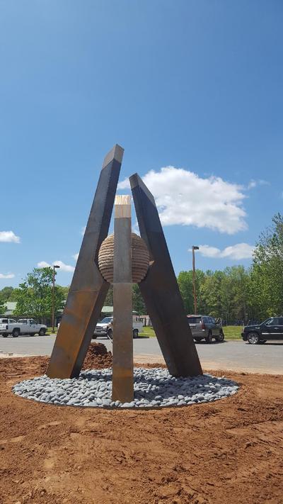 4/23/17: We're pleased to announce that NSG's Stephen Shachtman won this year's Sculpture at the River Market public art competition. Stay tuned to see it actualized and installed at the Southwest Community Center. This sculpture represents a culmination of parts forming a stronger, more impactful unit as a result. The graphic nature of the sculpture is ideal for both ease of viewing while in motion and creating an iconic sculpture for the Community Center campus. Because this site incorporates so many activities and houses several public buildings, the convergence of this is represented in this form - a central piece acts as the hub of all the opportunities the campus offers. At the heart of the three steel forms is a sphere representing the community. The Steel/Bronze portion of the “A” represents Arkansas. While the individual pieces of the flagstone sphere make up my notion its people. Fabricated in CorTen steel, with a Bronze cap at the point of each pillar. The tallest form measures approximately 16-feet high. The overall footprint will span approximately 10ft wide. The center sphere is composed of stacked flagstone pieces which create the stepped sphere form. (Not a perfect smooth sphere, but stepped to create sphere appearance.) The sphere structurally helps connect the three legs, which are then bolted into cement piers. I recommend contextualizing the artwork within the broader site by placing it in a large gravel circle of grey breeze, and planting karl foerster grasses within.