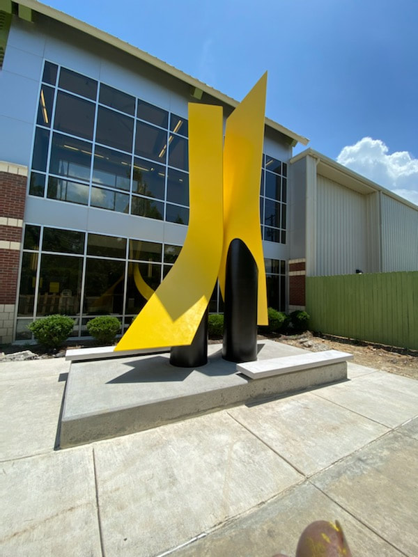 Kathleen Caricof and the National Sculptors' Guild are in Little Rock installing "Synergy" today!   We are so excited to see how the big yellow swoops enliven the courtyard of the West Central Community Center. To be enjoyed inside and out.  Two City Directors were on site to witness the installation, Doris Wright and Dean Kumpuris. (pictured) As always - a big thanks to the City of Little Rock lead by Jackie Collins and Leland Couch for their assistance with the installation. Fabrication of the sculpture was with Western Steel and Boiler in Denver. We worked with Fulton County Stoneworks in Arkansas for the custom stone benches that will encourage visitors to the center to sit near the sculpture and enjoy different perspectives of the work. NSG Public Art Installation #531 #NationalSculptorsGuild #NSG #CaricofSculpture #PublicArt #SculptureIsATeamSport #LittleRock #WestCentralCommunityCenter #Synergy
